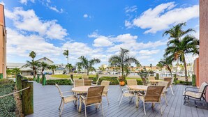 An outdoor patio with tables and chairs, overlooking a marina with boats and palm trees. - Waterfront Condo w/ Pool Access in Punta Gorda! (Punta Gorda)