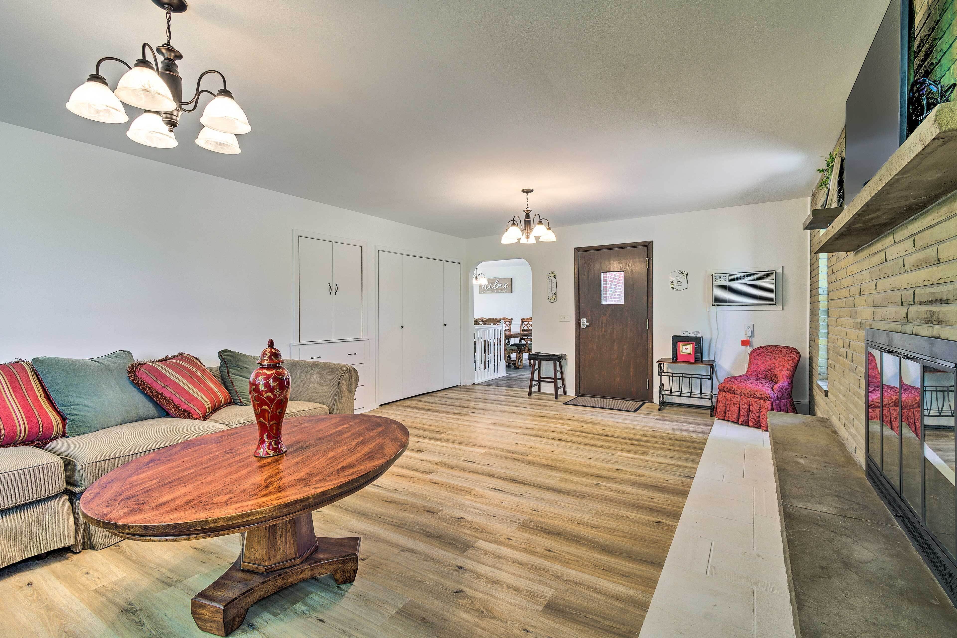 A spacious living area with a wooden floor, a round coffee table, a sofa set, and a fireplace.