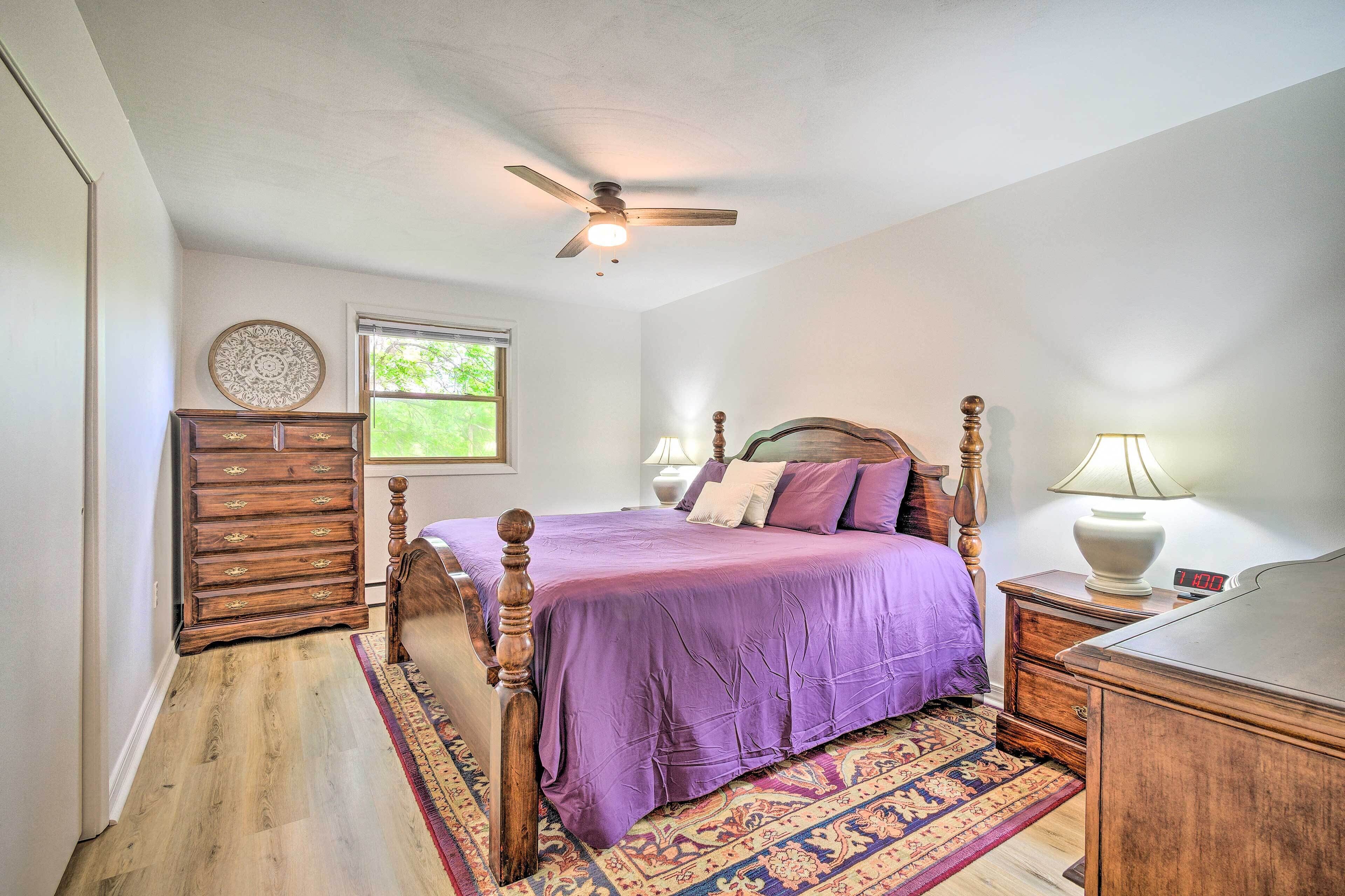A bedroom with a bed, dresser, nightstand, and a ceiling fan.