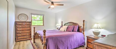 A bedroom with a bed, dresser, nightstand, and a ceiling fan.
