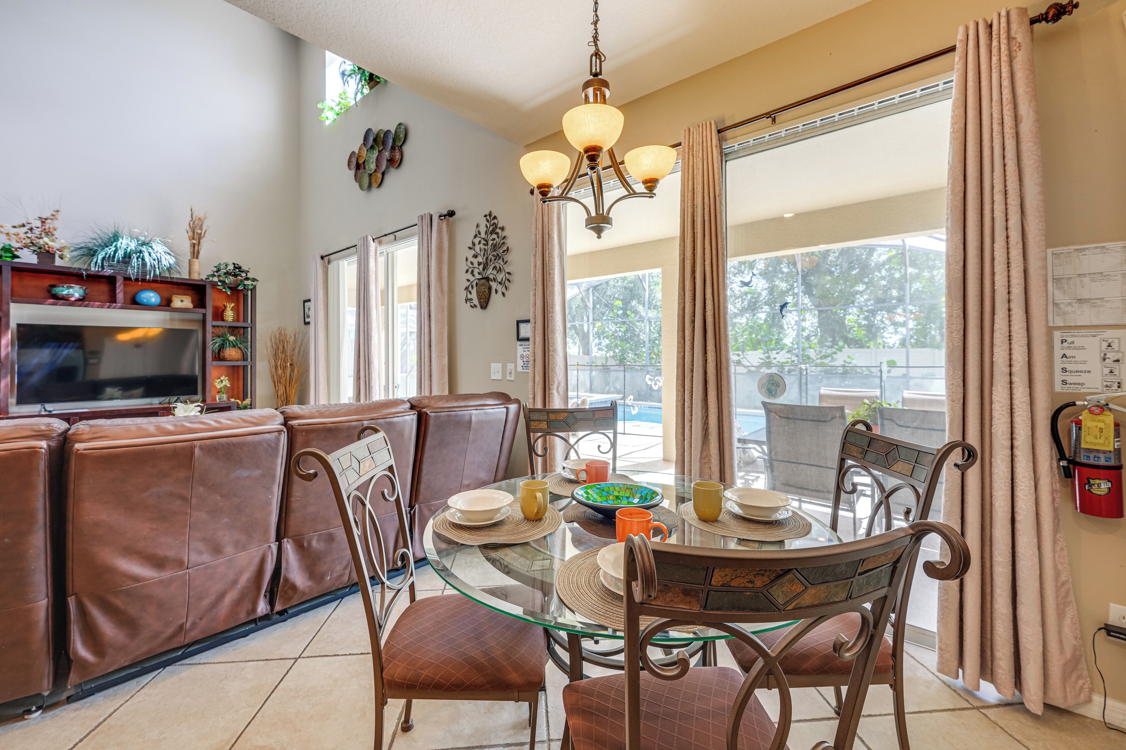 A dining area with a glass table, brown chairs, and a brown sofa.