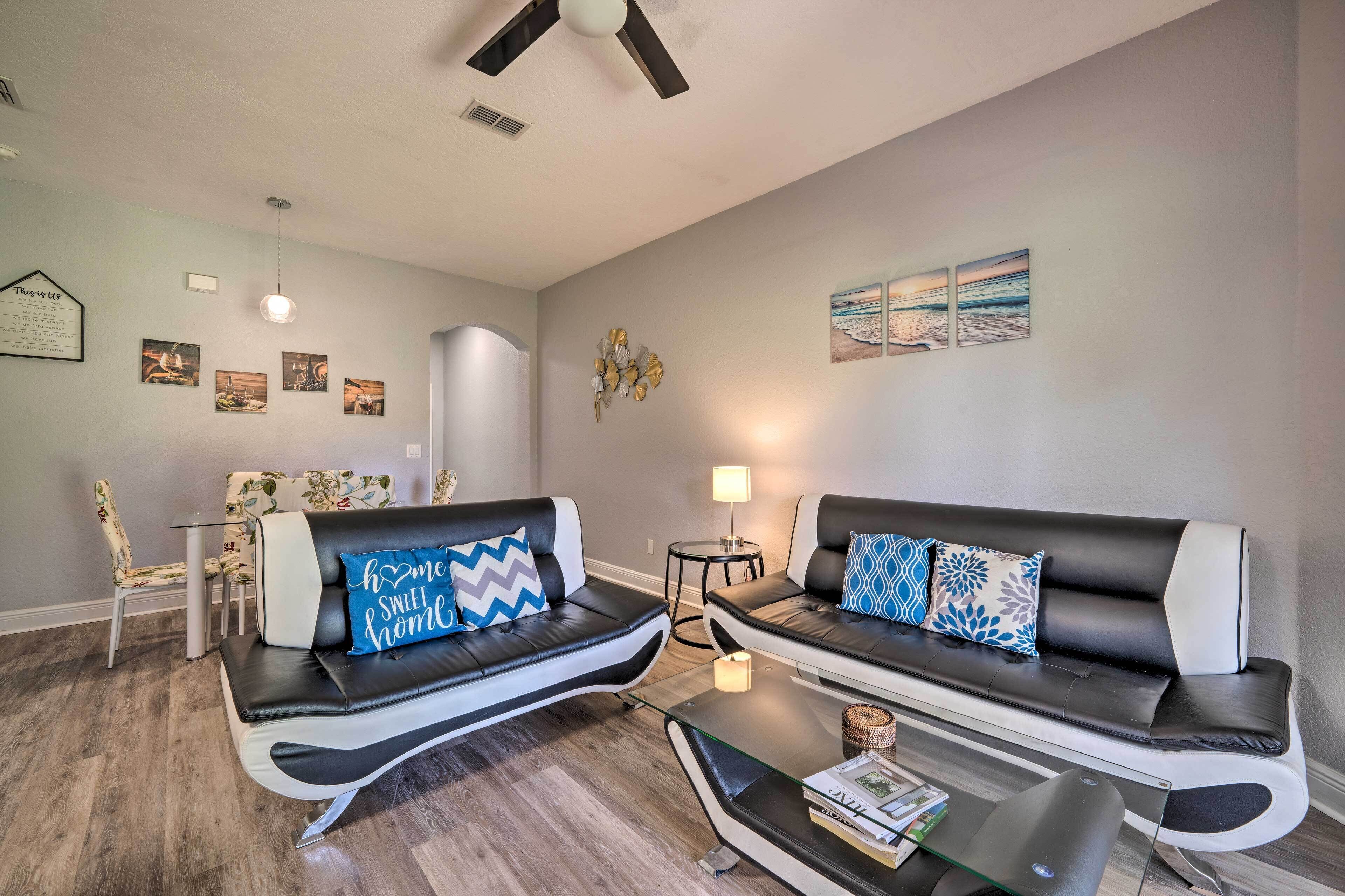 A modern living room with two black leather sofas, a glass coffee table, and a small side table with a lamp.