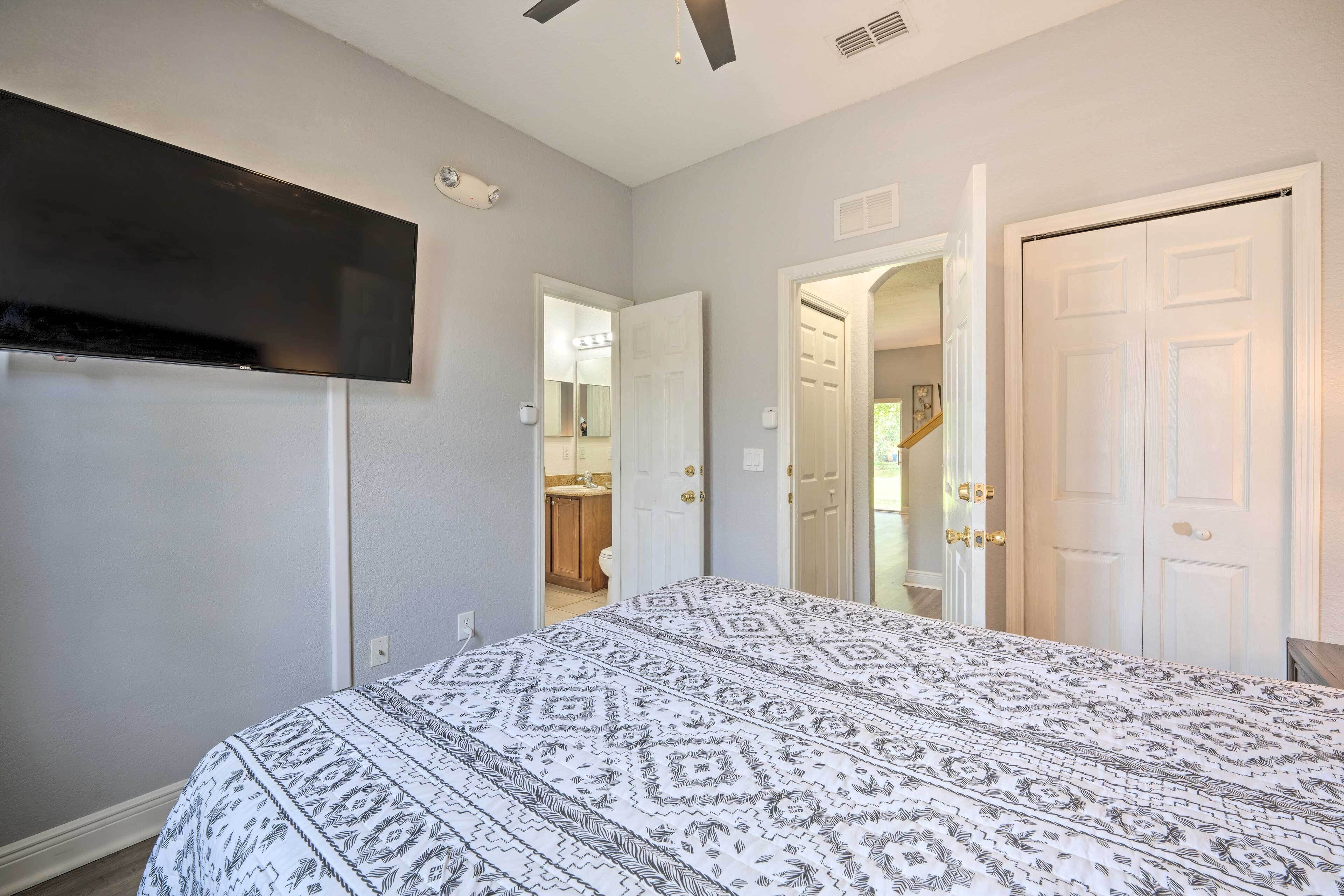 A bedroom with a bed, a TV mounted on the wall, and a door leading to a bathroom.
