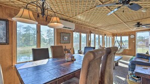 Un comedor rústico con una mesa de madera, sillas y vistas a un lago.