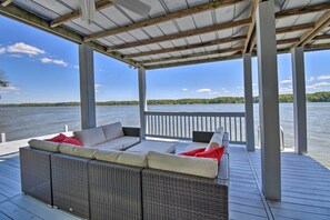 A covered outdoor seating area with wicker furniture and a view of a lake. - Bracey Home on Lake Gaston: Furnished 2-story Dock (Bracey)