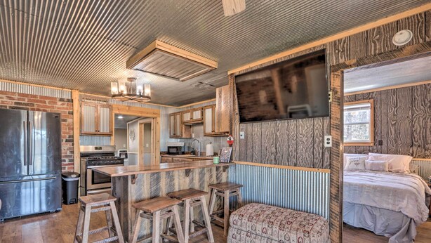 A spacious kitchen with a central island, wooden stools, and a built-in bench. - Rustic Retreat - Steps to Pomme De Terre Lake (Flemington)