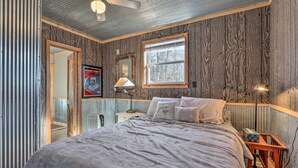A bedroom with a bed, a nightstand, a lamp, a window, and a ceiling fan. - Rustic Retreat - Steps to Pomme De Terre Lake (Flemington)