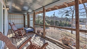 A covered porch with wooden rocking chairs and a view of the surrounding landscape. - Rustic Retreat - Steps to Pomme De Terre Lake (Flemington)