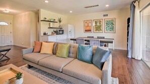 Una sala de estar con un sofá modular, una zona de cocina y una mesa de comedor.