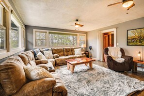 A cozy living room with a sectional sofa, a wooden coffee table, and a ceiling fan. - Country Escape: Log Cabin Near Kentucky Lake! (Gilbertsville)
