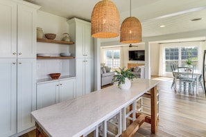 A kitchen with white cabinets, a marble countertop, wicker pendant lights, and a dining area with a table and chairs. - Cherokee Lake Home w/ Private Dock & Patio! (Mooresburg)