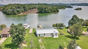 A lakeside property with a single-story house, a dock, and a grassy lawn.