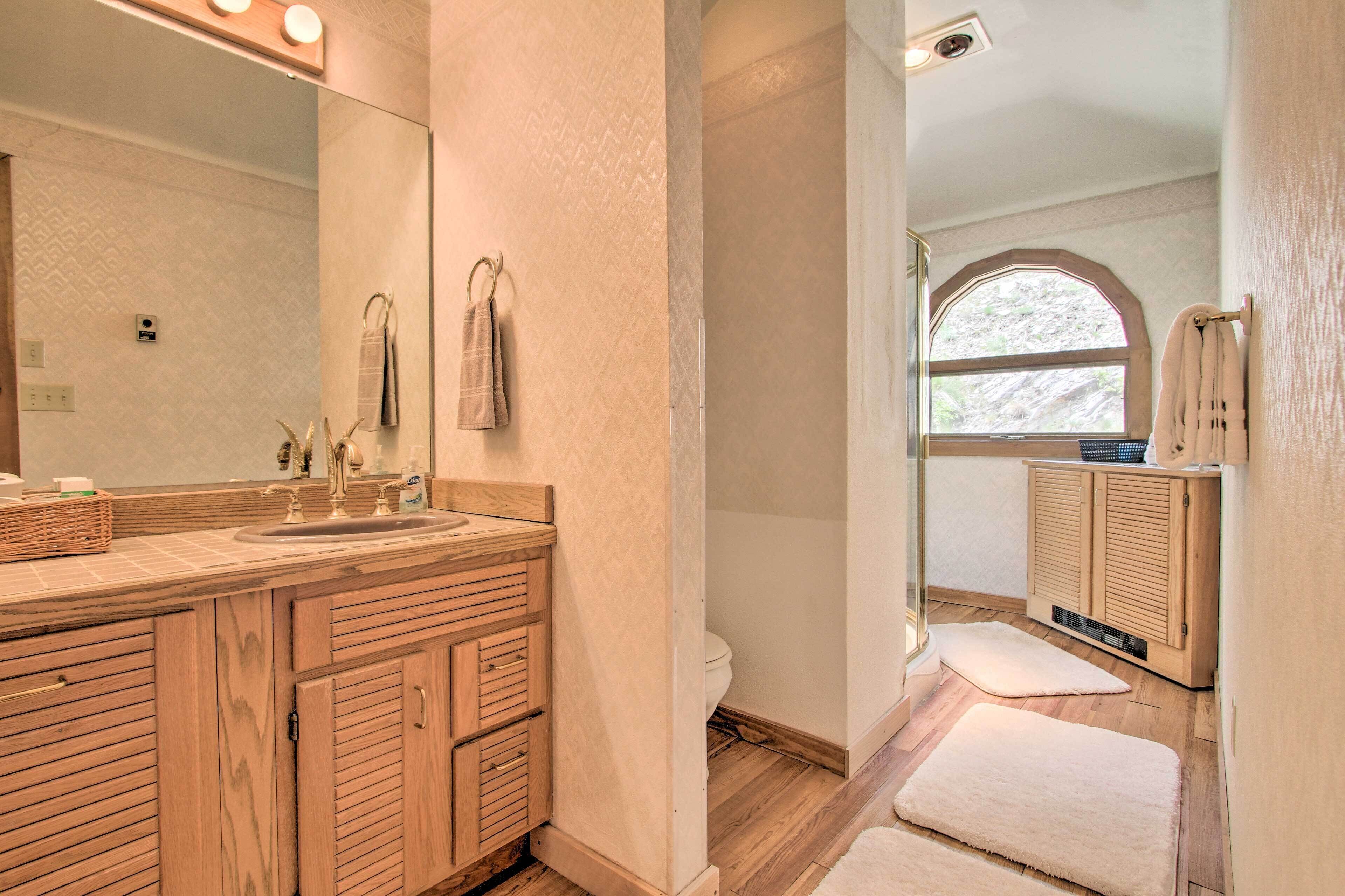 A modern bathroom with wooden cabinetry, a large mirror, and a window providing natural light.