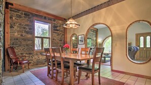 A dining area with a stone wall, wooden table, and chairs. - Historic Helena Retreat - Near Dtwn & Mt Helena! (Helena)