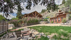 A two-story wooden cabin with a stone foundation, surrounded by a well-maintained garden and a gravel path leading to the entrance. - Historic Helena Retreat - Near Dtwn & Mt Helena! (Helena)