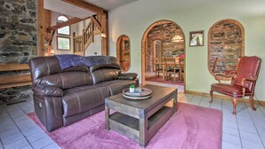 A cozy living room with a leather sofa, a wooden coffee table, and a red chair. - Historic Helena Retreat - Near Dtwn & Mt Helena! (Helena)