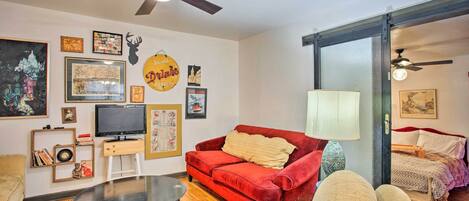 A living room with a red sofa, a TV, and various framed pictures on the wall.