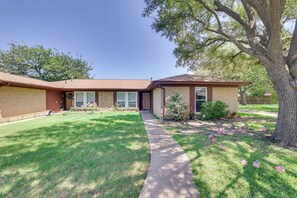 A two-story house with a front yard, a sidewalk, and a large tree. - Family Home in Fort Worth: Pets Welcome! (Fort Worth)