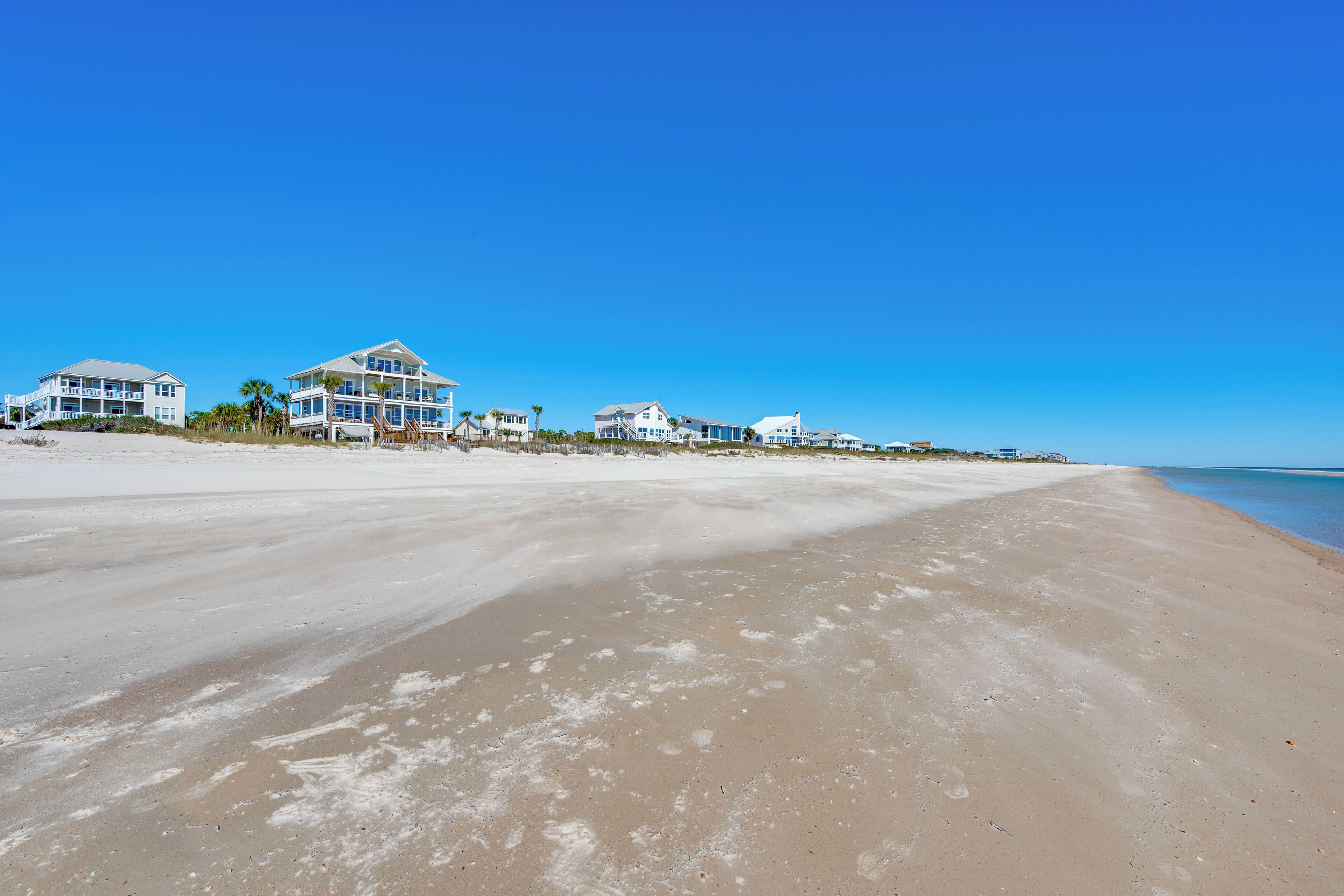 A beach with a row of white beachfront houses.