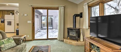 A cozy living room with a sofa, coffee table, TV, fireplace, and a view of the outside.
