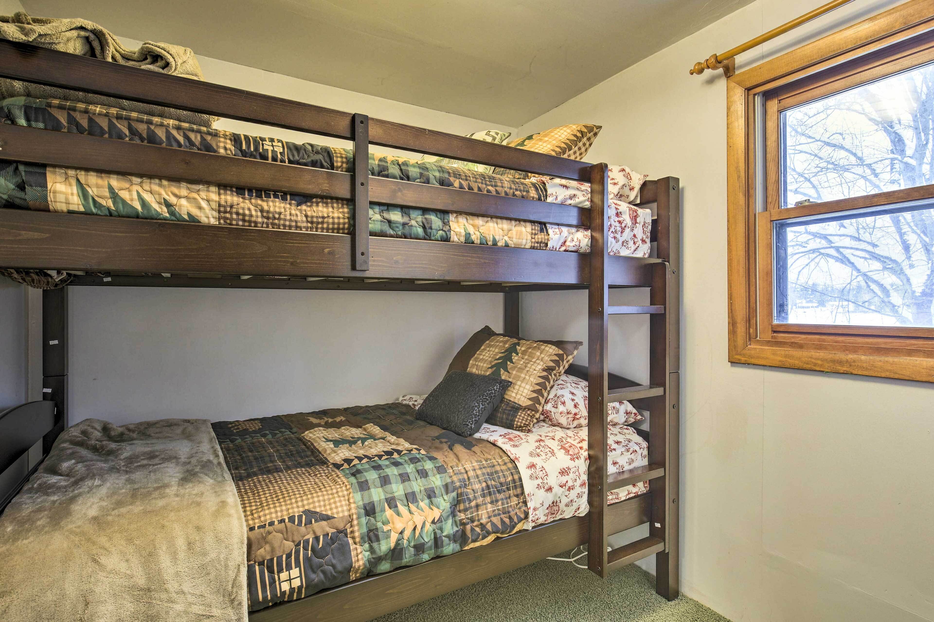 A bunk bed with a ladder, a window with a view of trees, and a shelf with items.