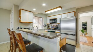 Una cucina moderna con isola centrale, sedie in legno, frigorifero in acciaio inossidabile e forno a microonde.