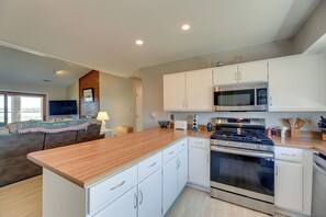 A modern kitchen with white cabinets, a stainless steel stove, and a microwave.