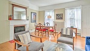 A living room with a fireplace, wooden furniture, a dining table, and a large mirror. - Pet-friendly Apt in 1850's Victorian Mansion! (Poughkeepsie)