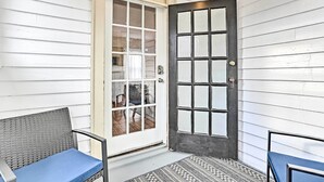 A porch with a white door, a blue bench, and a patterned rug. - Pet-friendly Apt in 1850's Victorian Mansion! (Poughkeepsie)