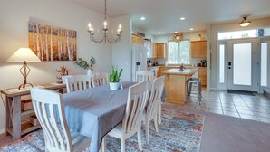 A modern kitchen with wooden cabinets, a central island, and a dining area with a table and chairs. - Charming Redmond Townhome w/ Resort Amenities (Redmond)