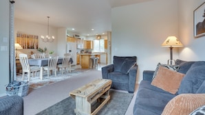 A modern living room with a grey sofa, a wooden coffee table, and a dining area with a white table and chairs. - Charming Redmond Townhome w/ Resort Amenities (Redmond)