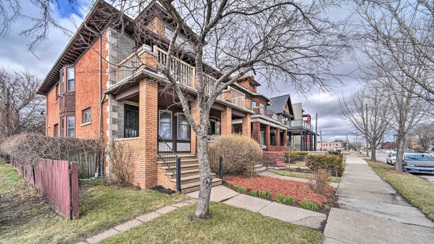 A row of brick townhouses with front porches, a wooden fence, and a sidewalk. - Charming Detroit Abode w/ Meditation Space! (Detroit)