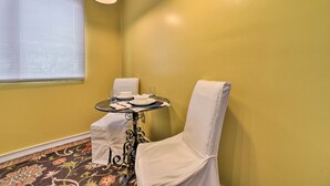 A corner room with yellow walls, a small table with a chair, and a window with blinds. - Charming Detroit Abode w/ Meditation Space! (Detroit)