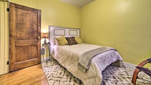 A bedroom with a wooden door, a bed with a headboard, a lamp, and a patterned rug. - Charming Detroit Abode w/ Meditation Space! (Detroit)