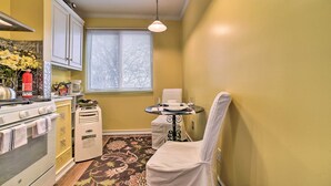 A compact kitchen with a stove, oven, and a small table with a chair. - Charming Detroit Abode w/ Meditation Space! (Detroit)