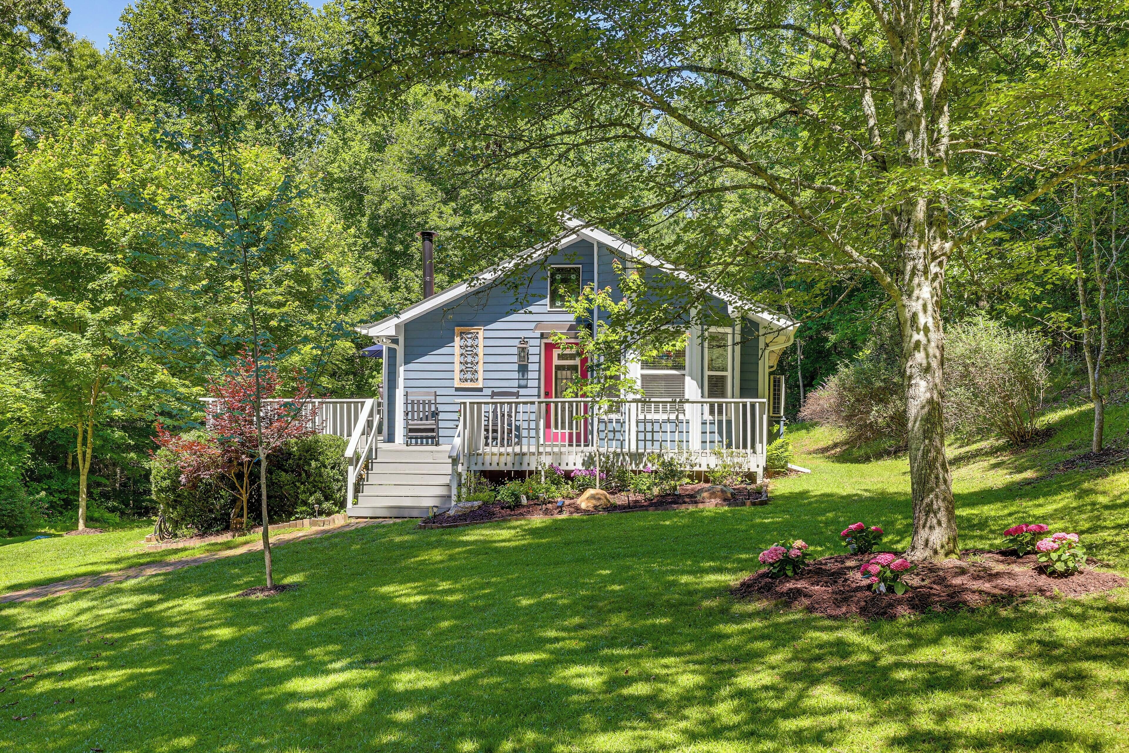 A house with a porch, surrounded by trees and a well-maintained lawn.