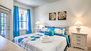 A bedroom with a bed, two bedside tables, a nightstand, a window with curtains, and wall art. - Family-friendly Escape w/ Smart TVs & Themed Rooms (Davenport)