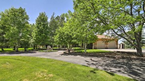 A residential driveway with a lawn, trees, and a house in the background. - Idyllic Idaho Falls Retreat w/ River Views! (Rigby)