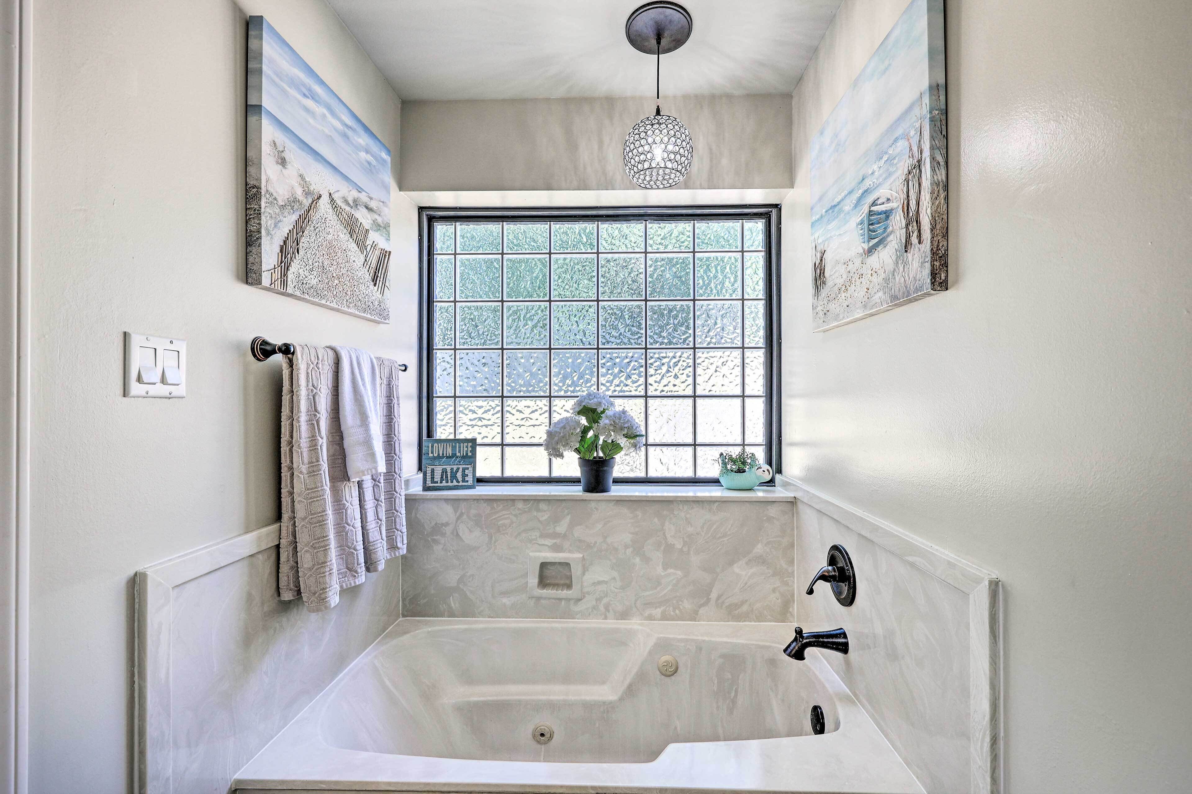 A bathroom with a large window, a bathtub, a sink, and a towel rack.