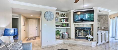 A spacious living room with a fireplace, a ceiling fan, and a television.