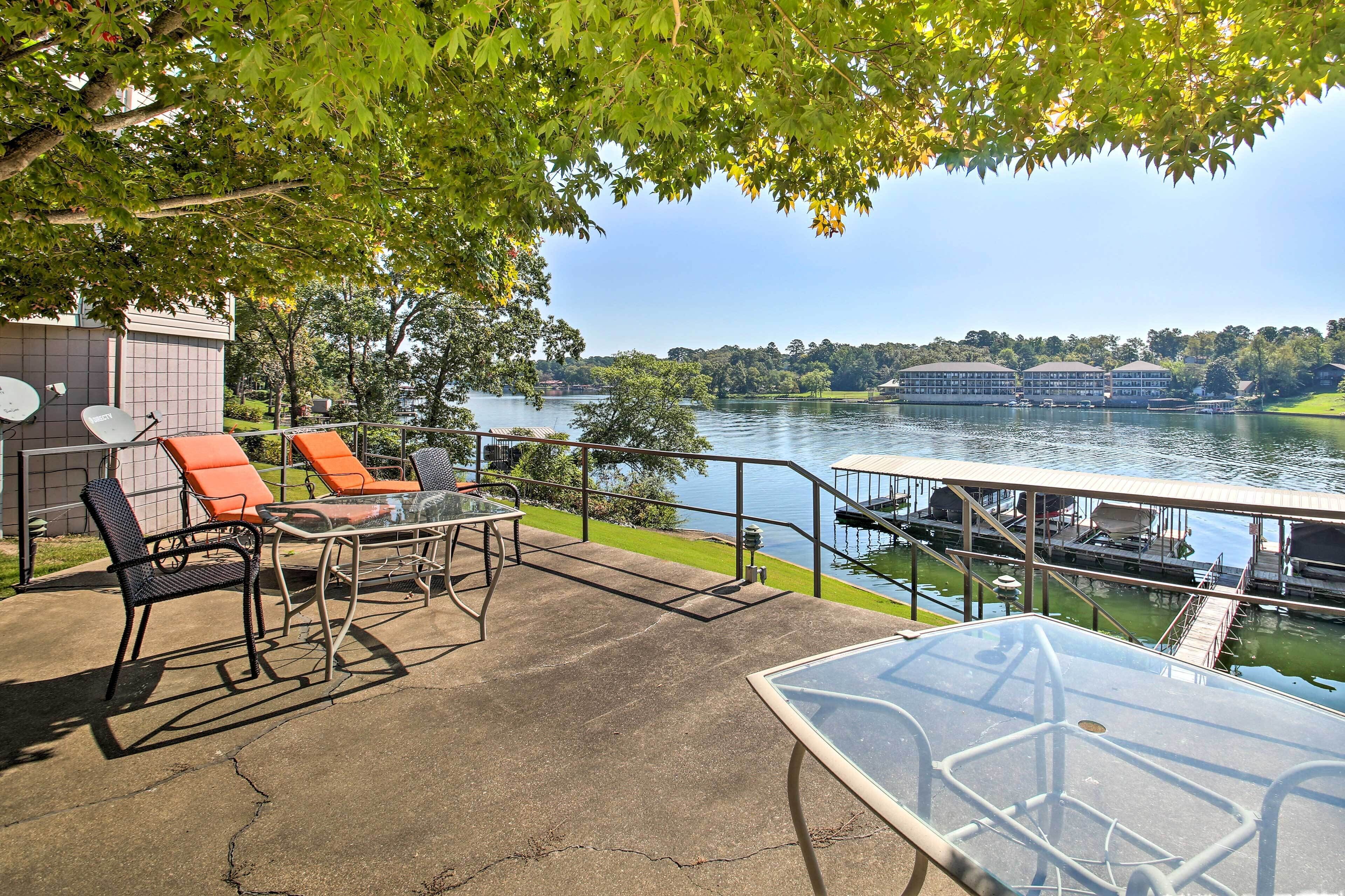 An outdoor patio with chairs and a table, overlooking a lake with boats.