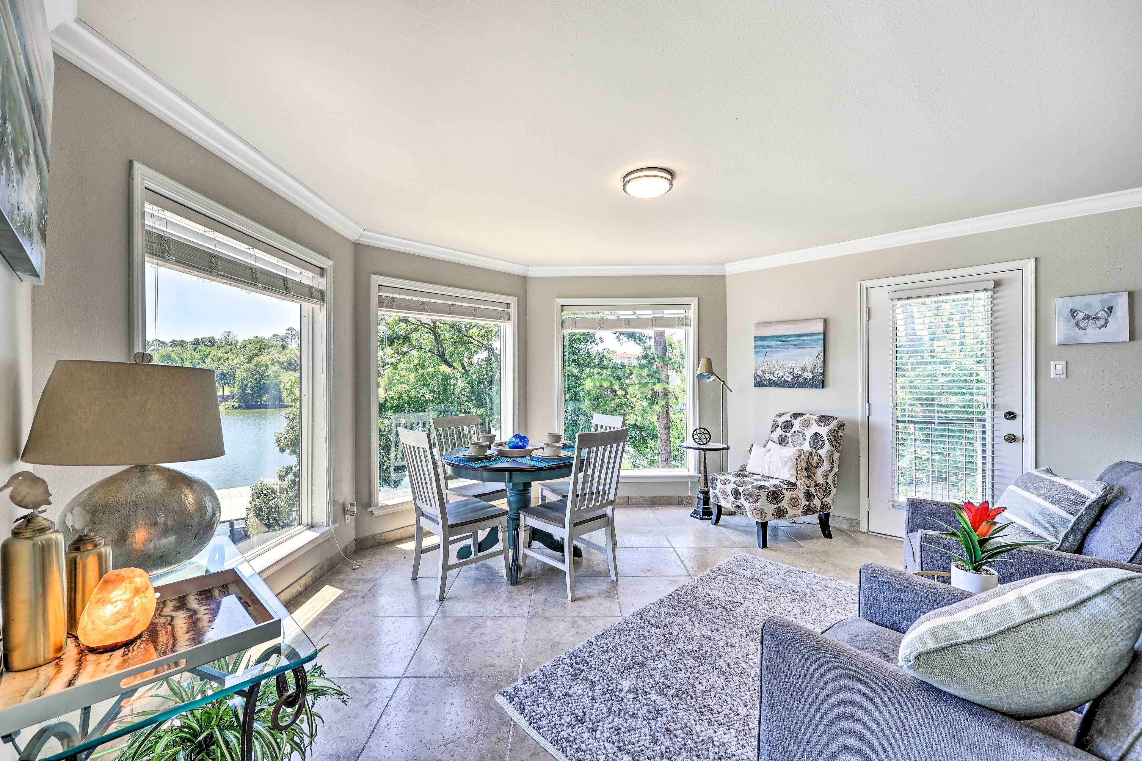 A spacious living area with a dining table, comfortable seating, and large windows offering a view of the outdoors.