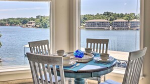 A dining table with chairs, a blue glass vase, and a view of a lake with buildings in the background. - 'lakeview Blue Oasis' in Hot Springs: Lake Access (Hot Springs)