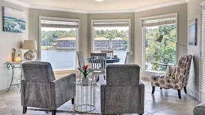 A room with a view of a body of water, two armchairs, a dining table, and a lamp. - 'lakeview Blue Oasis' in Hot Springs: Lake Access (Hot Springs)