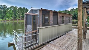 A wooden dock extending into a lake with a cabin-like structure on the dock. - Rustic-chic Riverfront Home w/ Dock, Deck & Canoes (Tallassee)