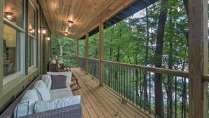 A wooden deck with a sofa and chairs, overlooking a forested area. - Rustic-chic Riverfront Home w/ Dock, Deck & Canoes (Tallassee)