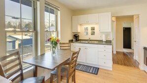 Una cocina moderna con armarios blancos, una mesa de comedor de madera y un ventanal con vistas al exterior.