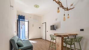Una sala de estar moderna con sofá, una mesa de comedor con sillas, televisor y una lámpara de techo original.
