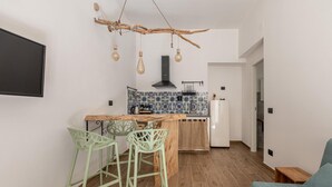 Cocina compacta con una isla central, dos taburetes de bar y un colgante.