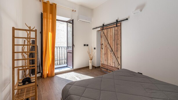 Un dormitorio con cama, escalera de madera, puerta corrediza tipo granero y vista por una puerta abierta.